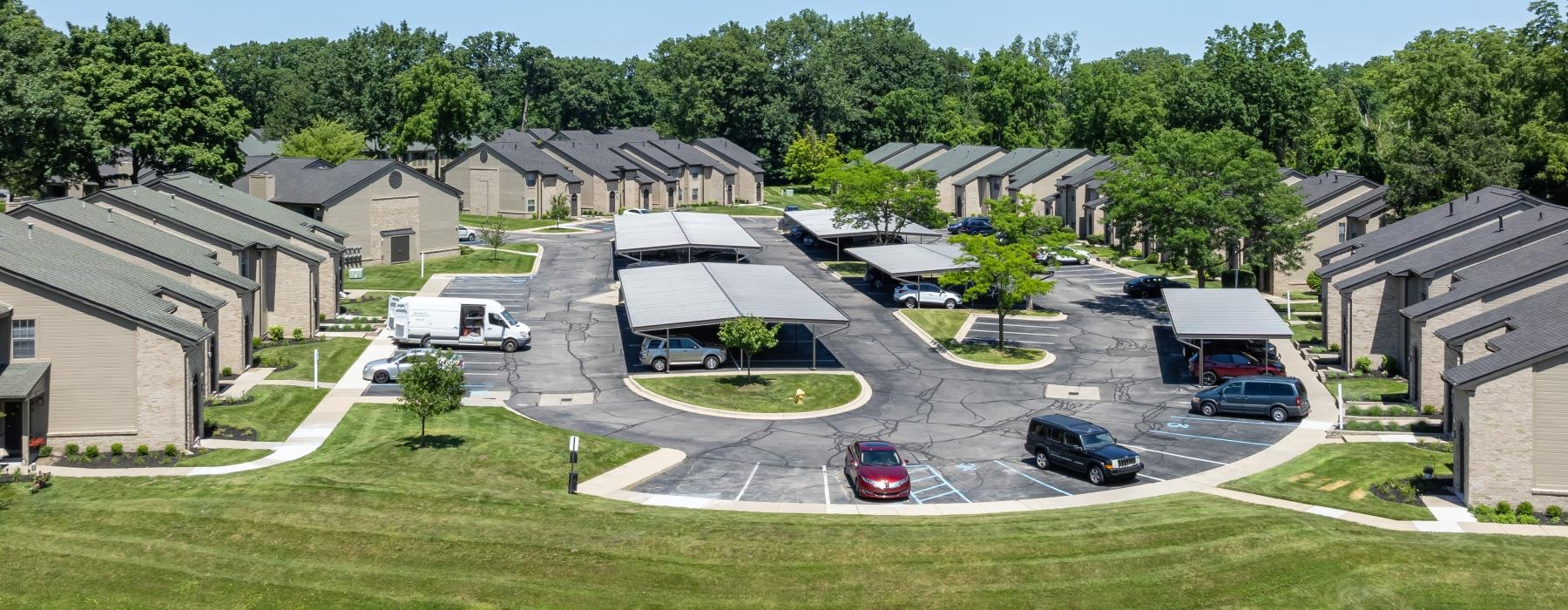 a group of houses with a parking lot and trees in the background
